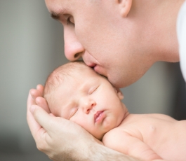 young man kissing newborn he holds his palms