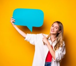 portrait happy young woman holding empty speech bubble standing isolated yellow wall